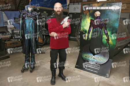 Martin Netter in Sternenflottenuniform mit Phaser. Im Hintergrund Originalkostüm aus 'Star Trek X'