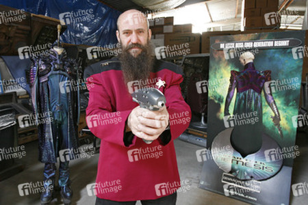 Martin Netter in Sternenflottenuniform mit Phaser. Im Hintergrund Originalkostüm aus 'Star Trek X'