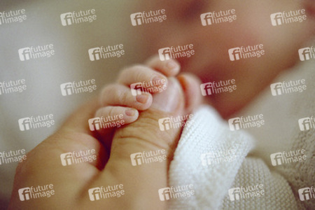 Vater hält die Hand seines neugeborenen Sohnes