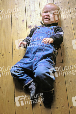 Weinender Junge auf Holzfußboden