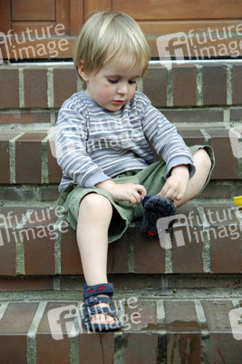 Junge zieht sich Schuhe an