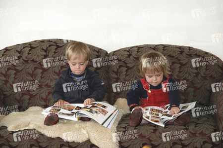Kinder auf einem Sofa beim Betrachten von Agentur-Bildkatalogen