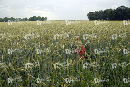 Zwei Kinder laufen durch ein Roggenfeld