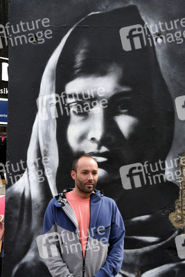 Victor Landeta präsentiert sein Mauersegment mit dem Porträt von Malala Yousafzai