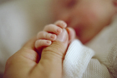 Vater hält die Hand seines neugeborenen Sohnes