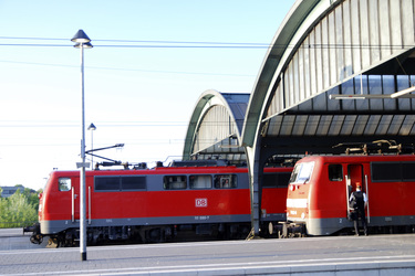 Zwei rote Lokomotiven im Bahnhof mit Zugführer