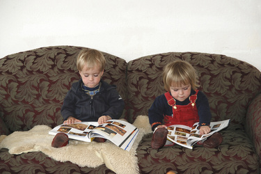 Kinder auf einem Sofa beim Betrachten von Agentur-Bildkatalogen