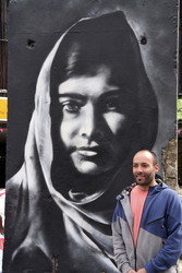 Victor Landeta präsentiert sein Mauersegment mit dem Porträt von Malala Yousafzai